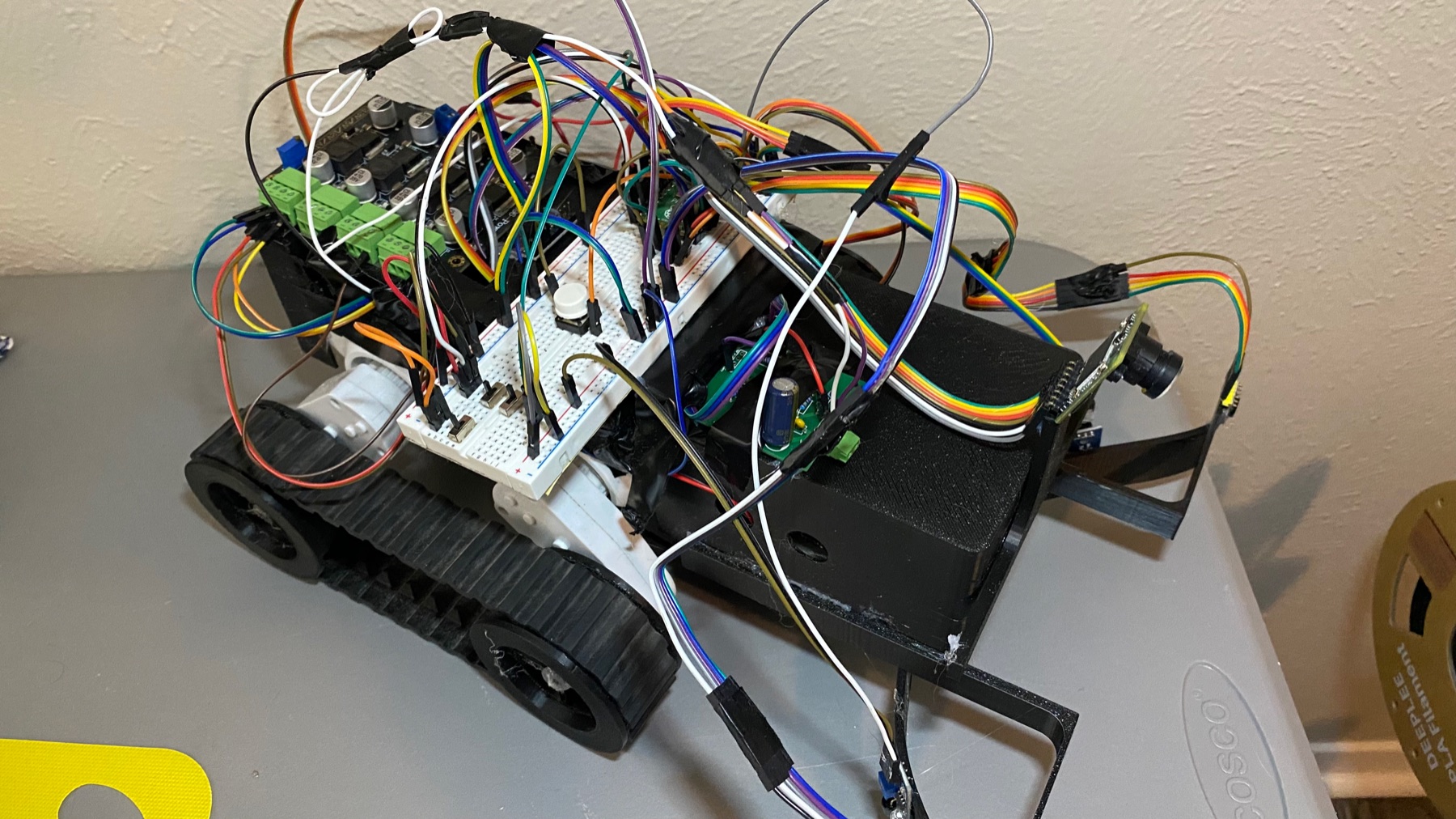 The rover: 3D-printed tracked chassis, camera, motor drivers and the wiring that holds it together.